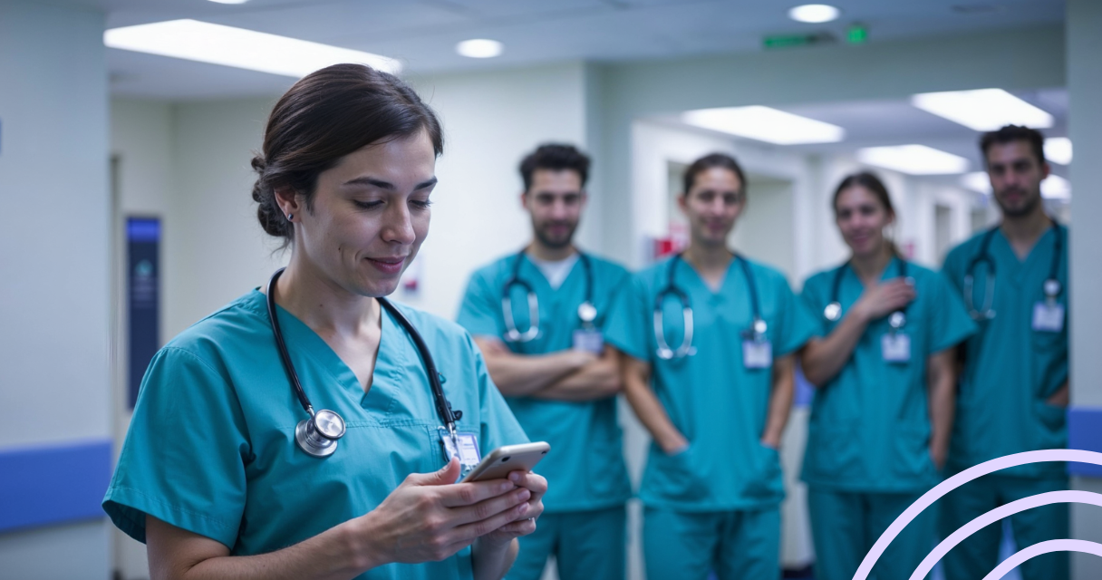 Nurse checking her phone for financial help options at work, with fellow nurses in the background
